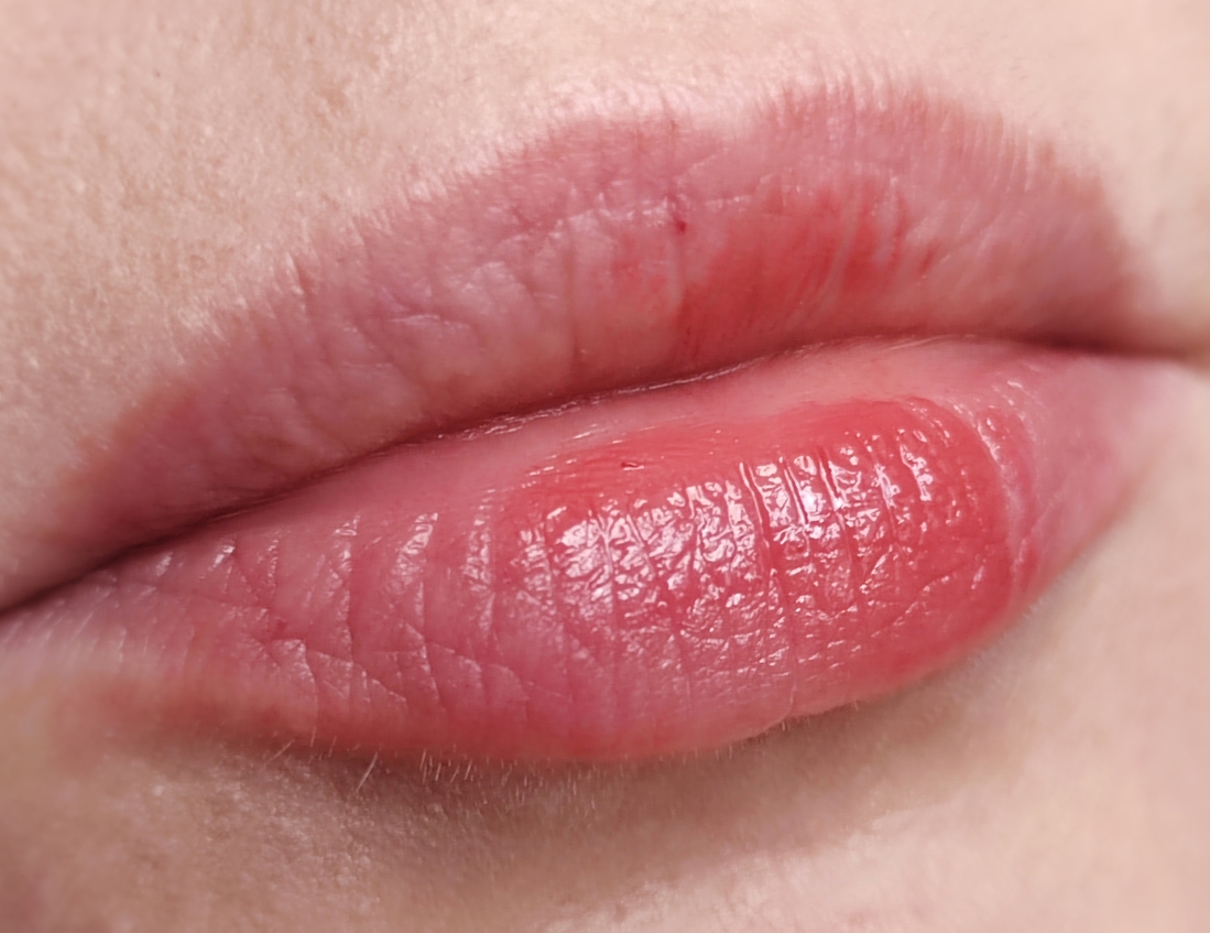 Лёгкое касание губ блеском из стика. И уже виден яркий красноватый пигмент